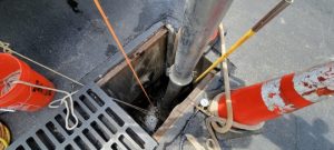 Maintenance worker clearing debris from a stormwater catch basin in spring