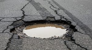 Pothole and cracked asphalt on a condo roadway during spring inspection
