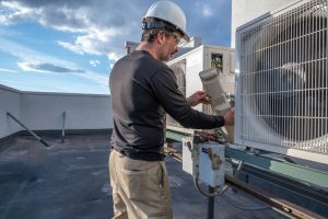 Technician inspecting HVAC equipment on a high‑rise rooftop.