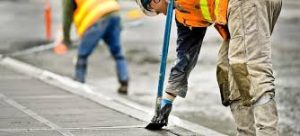 Worker repairing cracked walkway in a townhouse complex.